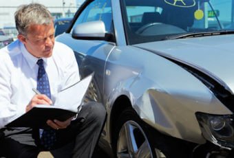 Insurance adjuster looking at a damaged car