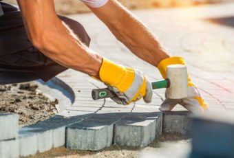 Construction worker laying paver blocks
